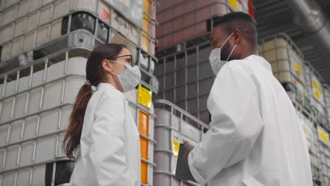 colleagues inspectors in safety mask and lab coat standing in chemical factory warehouse