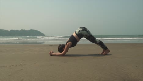 girl doing yoga on the beach with calming waves breaking along the coastline in background