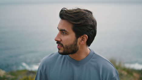 Portrait-man-enjoy-overcast-seascape-walking-on-sea-coast.-Guy-looking-at-ocean