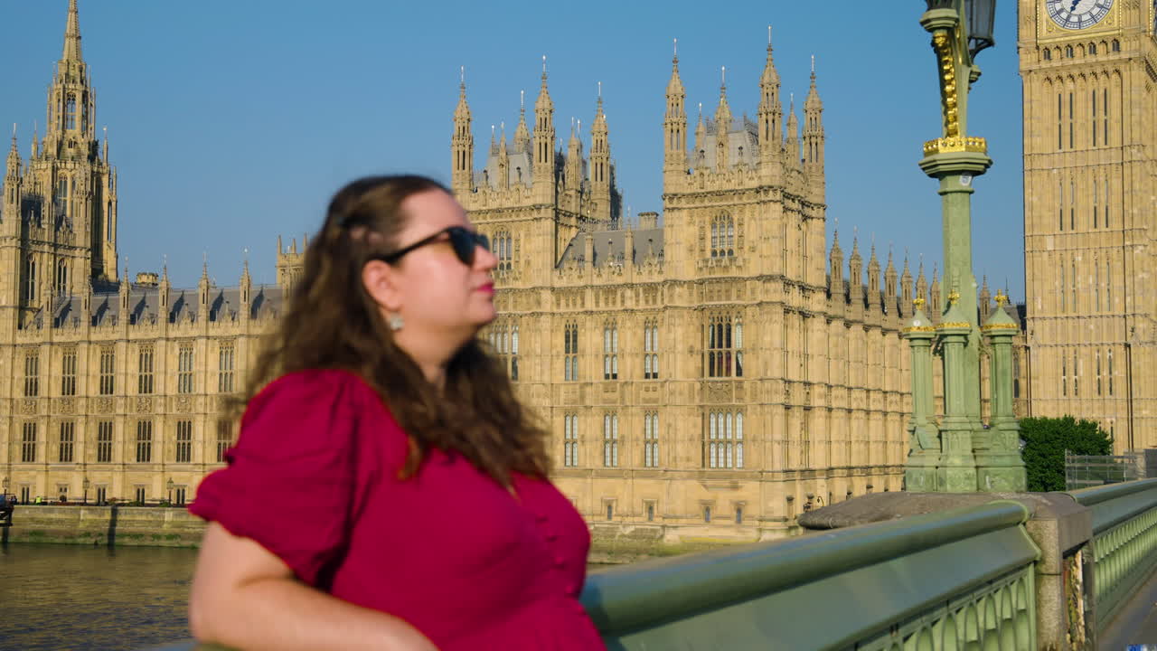 Woman Wearing A Red Dress At Westminster Bridge Near The Houses of Parliament And Big Ben In London, England, UK. Medium Close-up Shot