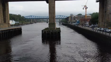 Incline-Hacia-Arriba-El-Video-Desde-El-Río-Tyne-Hasta-El-Puente-Ferroviario-Y-Peatonal-De-Alto-Nivel-En-Newcastle,-Inglaterra