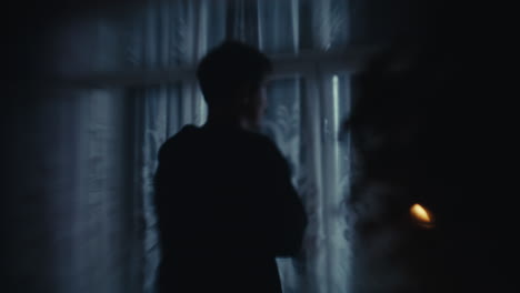 mysterious silhouette of a person by a window at night