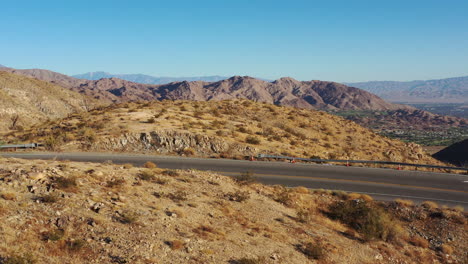 Disparo-De-Un-Dron-Volando-Bajo-Sobre-Una-Sinuosa-Carretera-De-Montaña-Del-Desierto-Hasta-El-Borde-Del-Acantilado