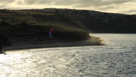 Surfers-Doing-Sea-Activities-On-Tropical-Hayle-Beach-In-Front-Of-Mountains,-Cornwall,-England