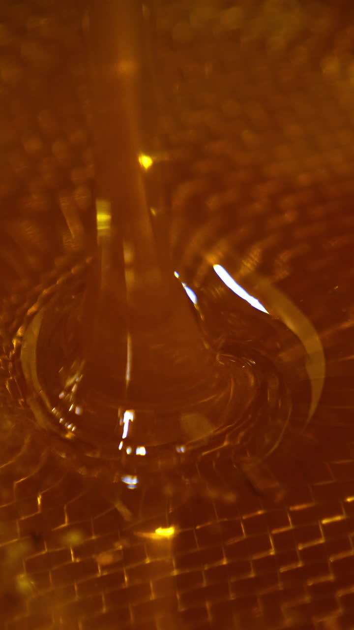 Freshly extracted honey flowing into the bowl. Close up. Healthy organic product filtering through the sieve. Vertical video