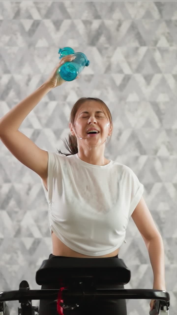 mujer cansada dispensa agua sobre la cabeza. mujer feliz corre en busca de alivio del calor generado durante el entrenamiento en la cinta de correr. sobrecalentamiento durante el entrenamiento