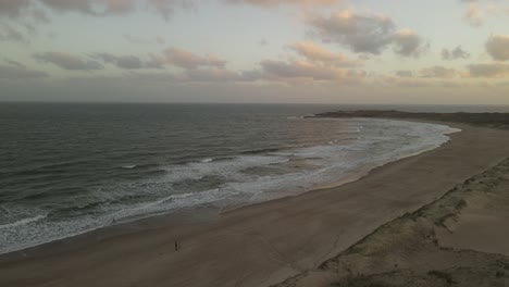 Vuelo-Aéreo-Sobre-La-Playa-De-Arena-Durante-La-Puesta-De-Sol-Nublada-En-Uruguay---Playa-La-Viuda,-Sudamérica