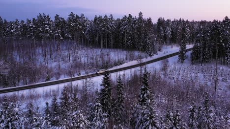 Los-Coches-Conducen-Por-La-Carretera-En-Un-Bosque-Brillante-Y-Nevado,-Tomas-Aéreas-De-Drones