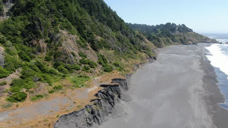 Top-down-aerial-view-of-people-walking-on-the-edge-of-the-ocean-shoreline,-Lost-Coast,-California