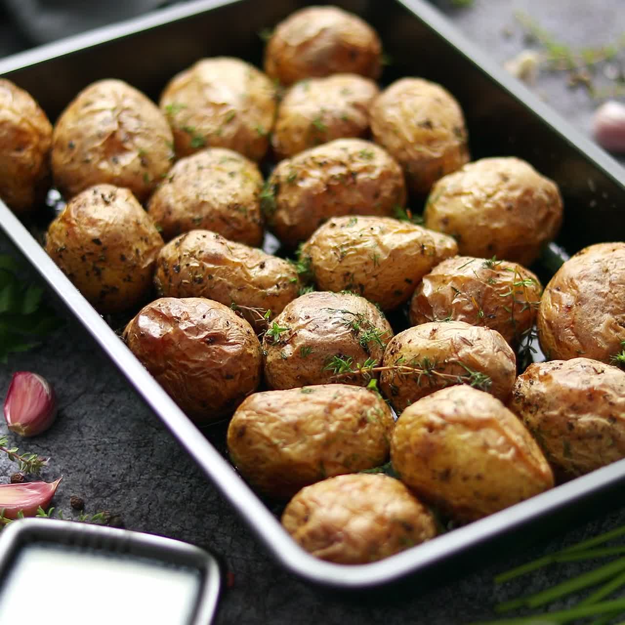 Gustose patate al forno fatte in casa, servite su un vassoio di metallo. Con varie erbe aromatiche, burro, aglio e sale.
