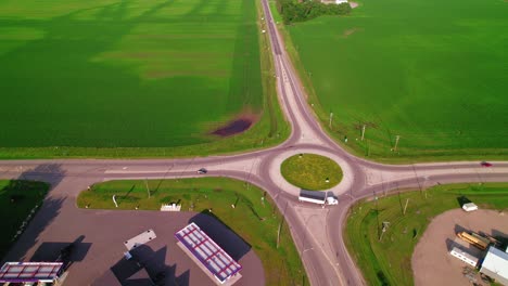 hopper trailer truck entering a roundabout in rural minnesota, with vast green fields surrounding it. american truckers in united states.