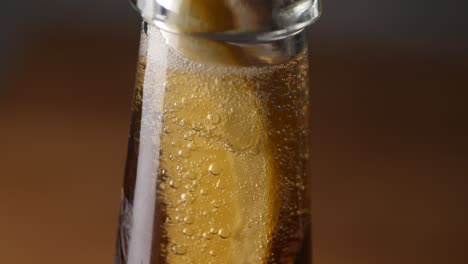 bubbles of carbon dioxide rise in the head of a fresh beer bottle - close up