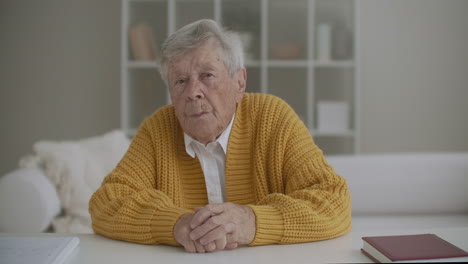 a grandmother with a yellow sweater looks at the camera and listens to the doctor advice on video communication with her head. station video conference