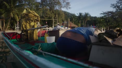 a person working on a longtail boat by a tropical beach
