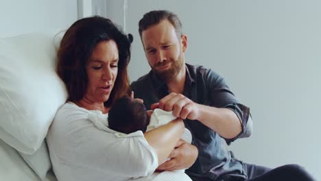 Front-view-of-Caucasian-couple-holding-their-newborn-baby-in-the-ward-at-hospital