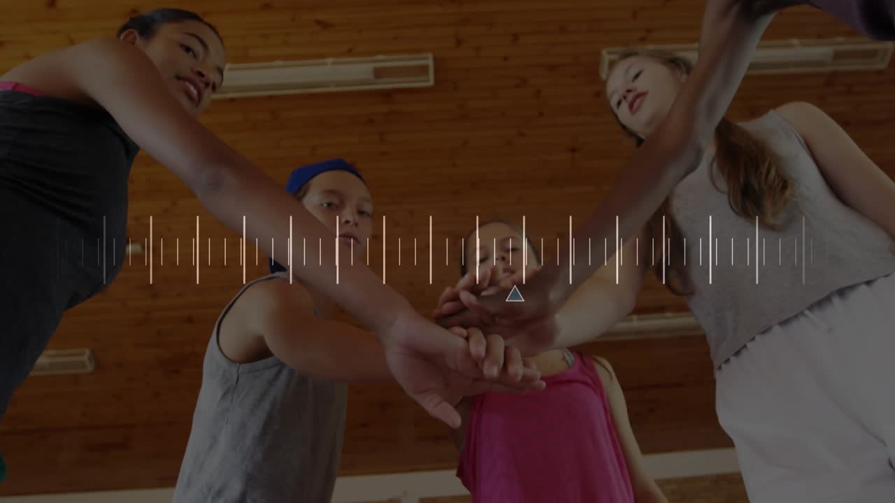 Five athletes reaching inward, stacking hands for unity under wood ceiling, waveform syncing hands