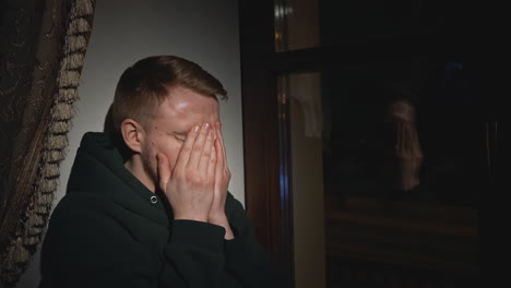 hombre sintiéndose triste junto a la ventana por la noche