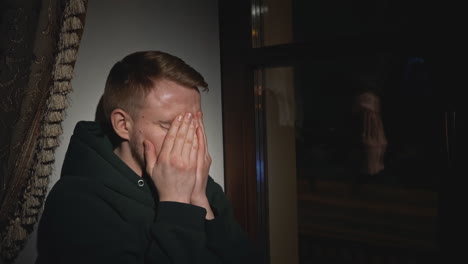 man feeling sad by the window at night