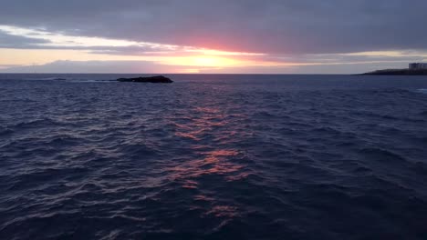 vuelo aéreo de drones hacia la puesta de sol con un pequeño bote de pesca y gaviotas volando en frente