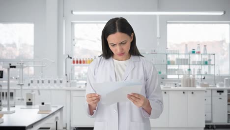 Stressed-Indian-female-scientist-reading-reports