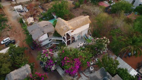 Toma-Aérea-En-Espiral-De-Una-Choza-En-Puerto-Escondido,-Oaxaca-México-Durante-La-Puesta-De-Sol