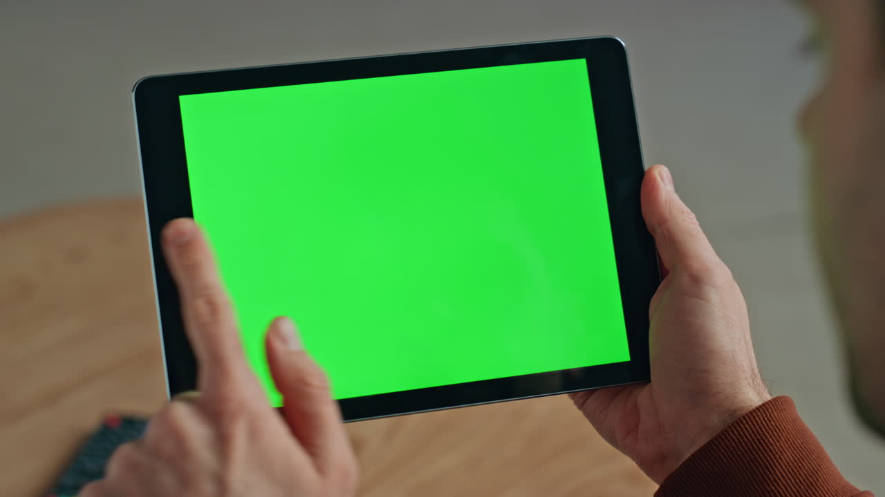 Freelancer hands swiping green screen tablet searching information at workplace