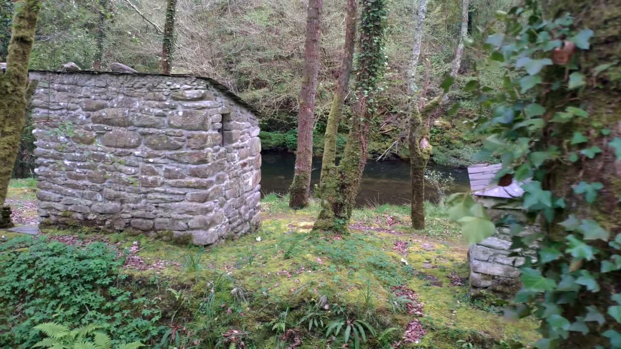 cabaña horno refugio de montaña construido con piedras cerca del río sor con bosque y robles.