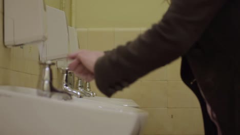 washing hands in a public washroom sink with soap dispenser