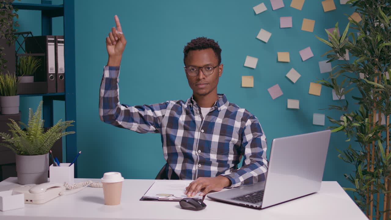 Serious person pointing up with index finger at office desk