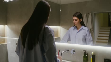 woman brushing teeth in bathroom