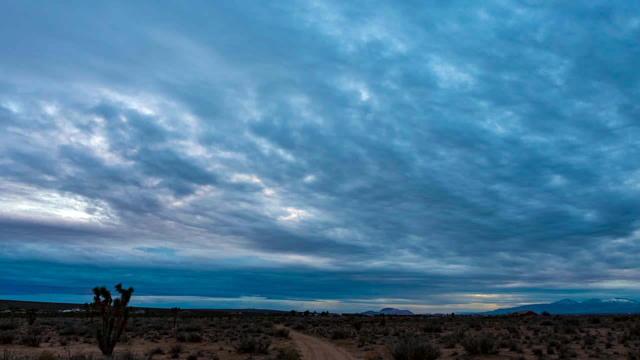 paisaje nuboso al atardecer sobre el paisaje árido y escarpado del desierto de mojave en una noche nublada - lapso de tiempo de gran angular