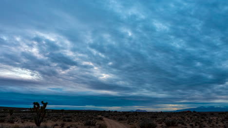 Sunset-cloudscape-over-the-Mojave-Desert's-arid-and-rugged-landscape-on-an-overcast-evening---wide-angle-time-lapse