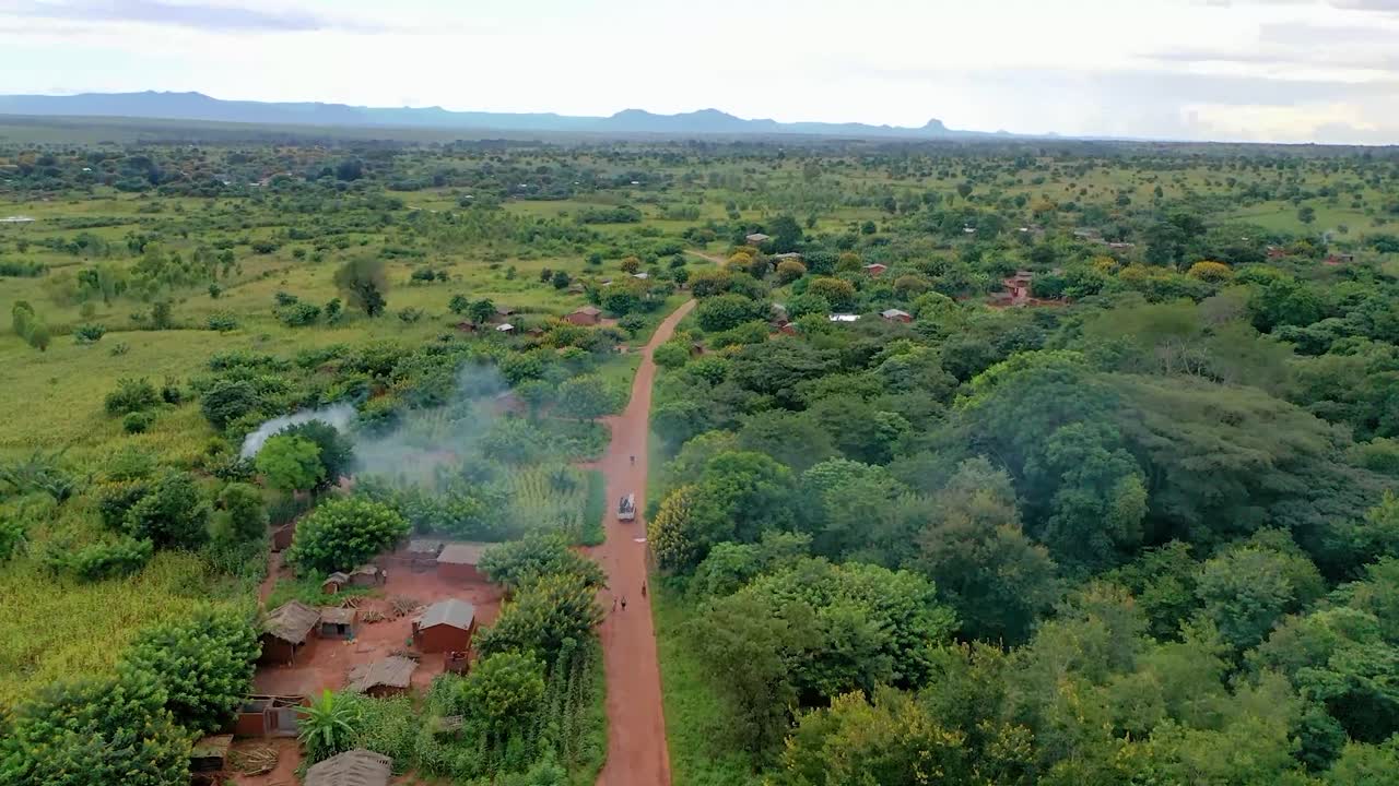 drone volando sobre un pueblo con un auto conduciendo hacia él