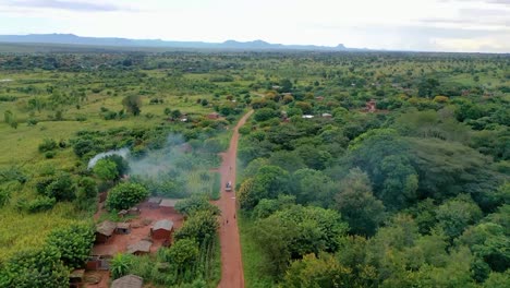 Drone-Volando-Sobre-Un-Pueblo-Con-Un-Auto-Conduciendo-Hacia-él