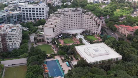 aerial footage of a five-star hotel complex that resembles a resort in the middle of the city, complete with trees and a swimming pool