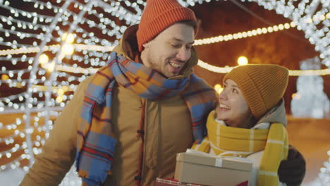 pareja feliz caminando con regalos de navidad al aire libre y besándose