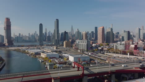 Forwards-fly-above-highway-bridge.-Aerial-view-of-Long-Island-City-train-station-and-downtown-skyscrapers-in-background.-Queens,-New-York-City,-USA