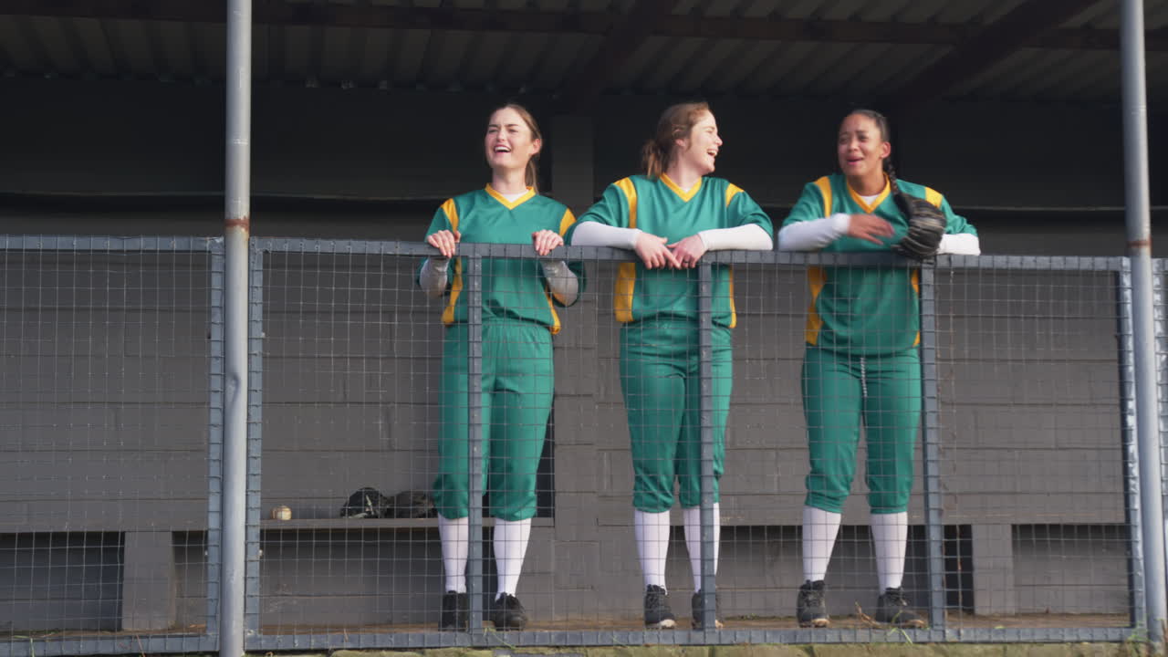 Multiracial female baseball players watching the game of baseball, supporting on a pitch