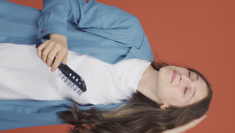 vertical video of young woman combing her hair.