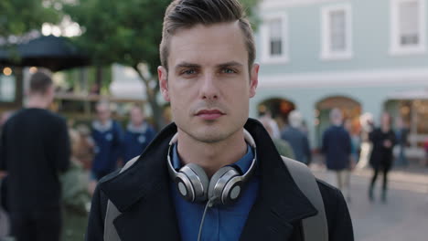 close up portrait of attractive young caucasian man staring looking serious at camera in busy urban city background