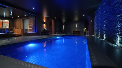 low-orbiting shot of an indoor pool in a villa with blue led lights in france