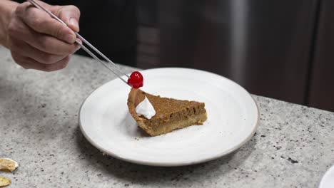 the pastry chef and his apprentice prepares recipe for a slice of pumpkin brownie cream pie dessert with cream and cherry