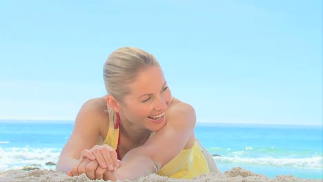 mujer rubia acostada en la arena