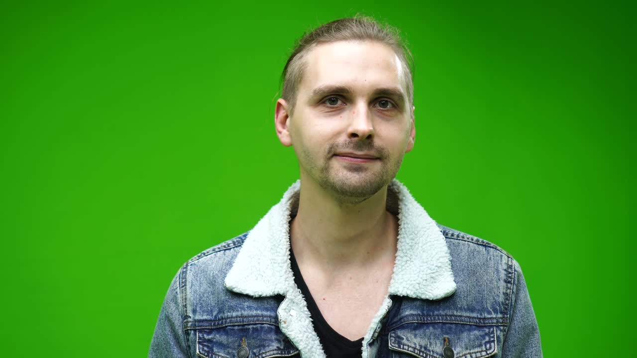 hombre guapo en chaqueta de jean de pie solo en el fondo de la pantalla verde