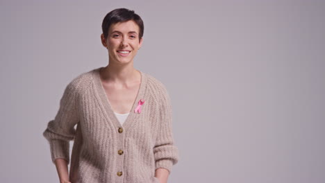 studio portrait of smiling young woman wearing pink breast cancer awareness ribbon against white background 3