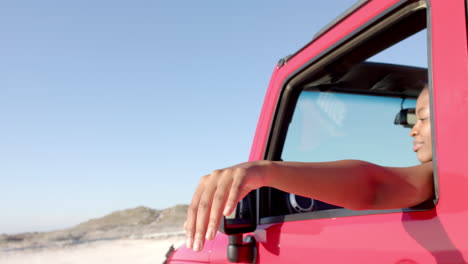 El-Brazo-De-Una-Persona-Se-Extiende-Desde-Un-Vehículo-Rojo-En-Un-Viaje-Por-Carretera,-Señalando-Al-Aire-Libre.