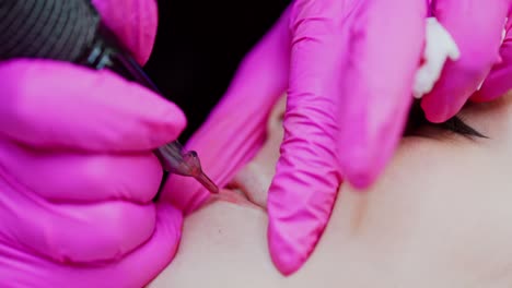 microblading procedure. applying permanent make up tattoo on young girl lips. hands in protective gloves of a cosmetologist doing lips tattoo. close-up.