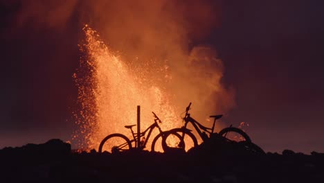 mountain bike silhouettes in front of eruption iceland