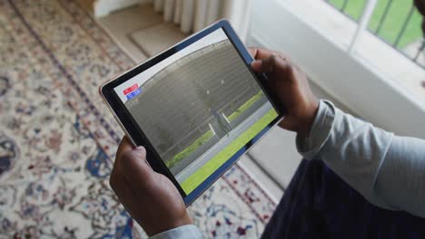 compuesto de un hombre sentado en casa, viendo el evento de jabalina de atletismo en la tableta