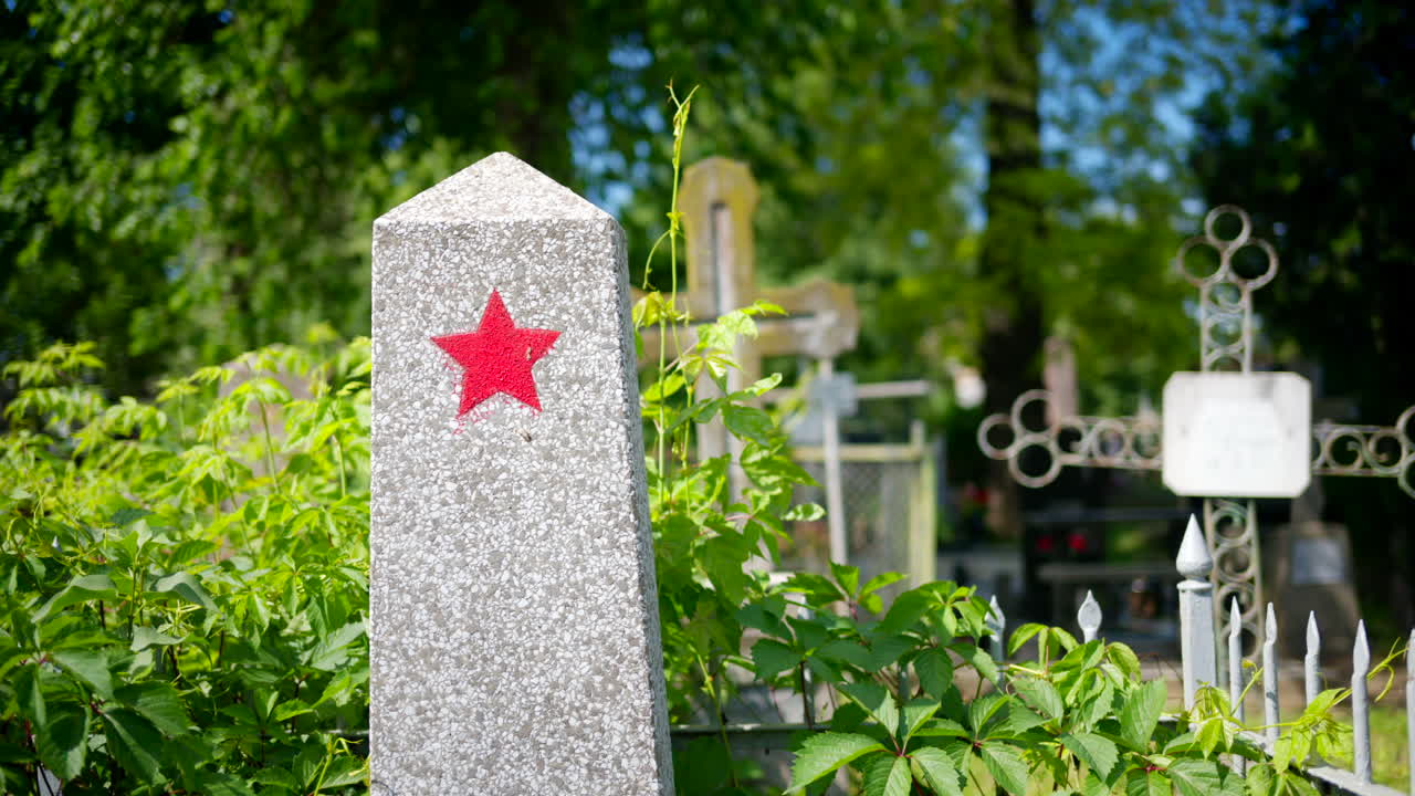 A soviet headstone surrounded by greenery in a cemetery